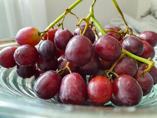 Red grapes on a glass plate in the living room. Healthy fruit, suitable for a conscious diet.