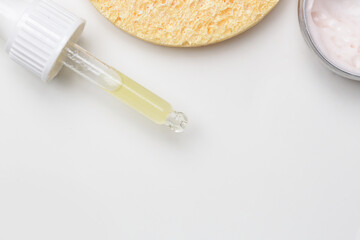 Nourishing and hydrating facial serum, antirid cream and facial sponge, top view with copy space.
