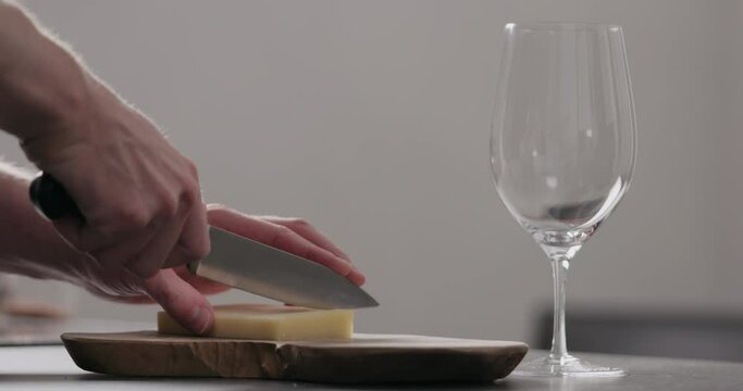 Slow motion man hands cutting vintage cheese on oliveboard with wine glass