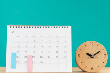 close up of calendar and alarm clock on the table with green background, planning for business meeting or travel planning concept