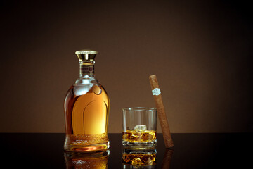 close up view of cigar, bottle of whiskey and a glass aside on color back. 