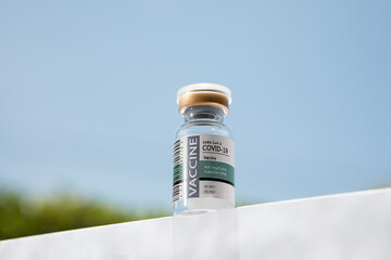NO LOGOS OR TRADEMARKS!  SELF MADE LABELS! Close up view of ampule with covid vaccine on blue back