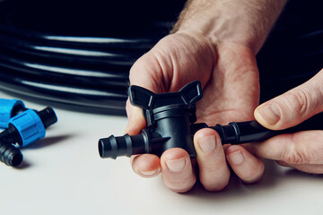 Preparing for planting in early spring. Male hands in the frame hold a faucet for drip irrigation. DIY drip irrigation system assembly