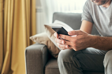 Man using mobile phone at living room sofa