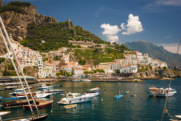 Fototapeta na wymiar Amalfi Italy harbor with boats in foreground and town in background with blue sky and clouds