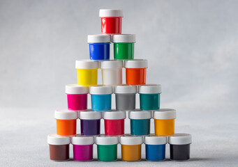 Pyramid of colorful gouache cans on gray background. Arts, schools and education. copy space