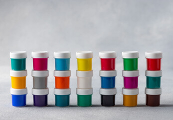 Set of colorful gouache in cans stacked in row on gray blurred background. Arts, schools and education. place for text or design