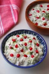 Pomegranate and Cucumber Raita. Indian Fresh sauce or condiment called Raita. Yogurt mixed with grated cucumber, onions,  pomegranate, and spices. Garnished with fresh coriander. Copy space.