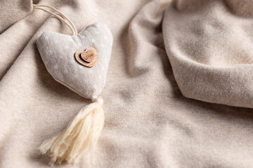 Mothers day background with soft beige heart on fabric backdrop. Symbol of love. soft focus. close-up