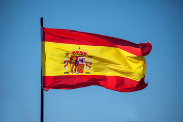 Spanish national flag waving against blue sky