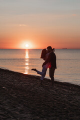 couple hugging look at sunset above sea