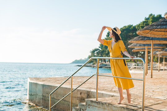 young pretty woman in yellow sundress at sea beach