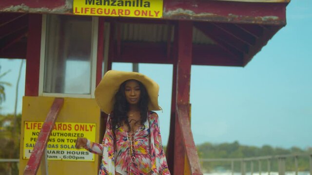 A young African Queen walks down from a lifeguard booth in a sexy bikini