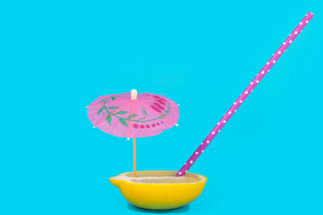 Lemon cut in half with straw and cocktail umbrella. Summer fresh juice concept.