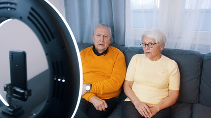 Elderly couple giving an interview or recording video message for family. High quality photo