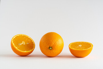 Close-up of fresh oranges, whole and halved on a white background with copy space