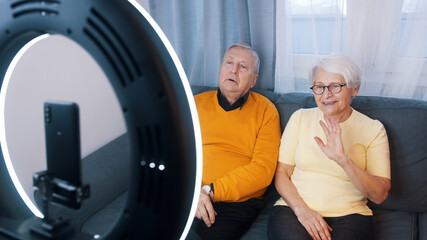 Happy grandparents waving to smartphone camera. Recording video message for family. High quality photo