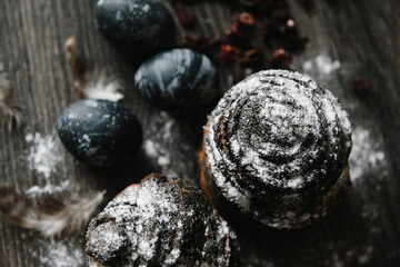 easter cake with poppy seeds in powdered sugar on a wooden table top with blue-painted eggs