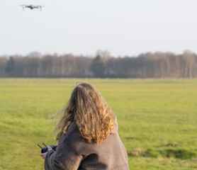 Drohne wird auf einer grünen Wiese von einer Pilotin geflogen