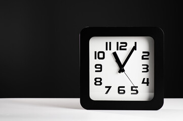 black square clock on white table, gray background, empty space, place for text