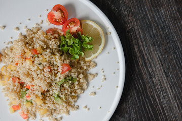 a plate with kenoa salad and vegetables on the background of a wooden table top