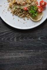 a plate with kenoa salad and vegetables on the background of a wooden table top