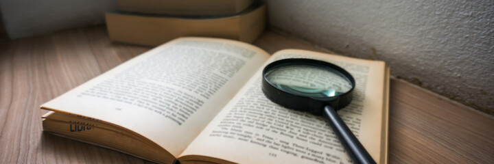 Fototapeta premium Books and a magnifier Research concept. Magnification glass over a opened book.