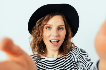 Fashionable young woman wearing black fedora and striped shirt making selfie