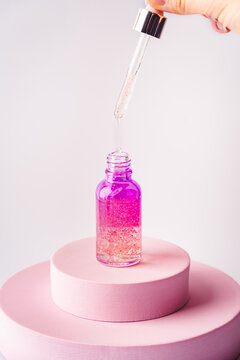 Glass cosmetic bottle with oil or serum for skin care on special podium of pink color. Natural skin care concept.