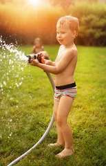 Foto op Aluminium Joyful kids enjoying summer shower in the garden © konradbak