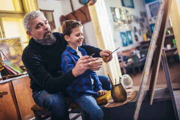 Father and son working and painting together in art studio