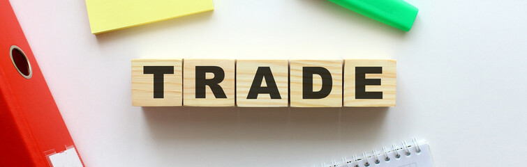 Wooden cubes with word TRADE on the office desk. Folder and other office supplies.