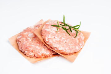 Semi-finished product, chicken meat fast cooking.Two pieces of chicken hamburgen on cave paper on a white background in a rosemary branch with a place for text. Fast food for home and restaurants.