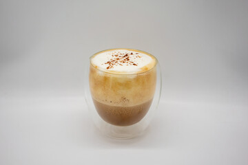 Hot coffee with milky foam sprinkle with cocoa power for decoration in double wall glass isolated on white