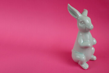 ceramic figurine of blue easter bunny on pink background side view