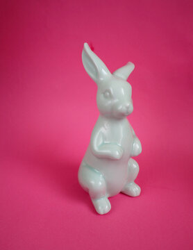 ceramic figurine of a blue Easter bunny on a pink background side view . Easter holiday