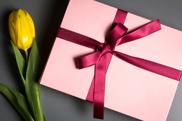 Pink gift box with a red ribon on a dark background.