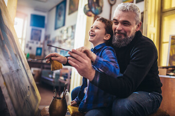 Father and son working and painting together in art studio