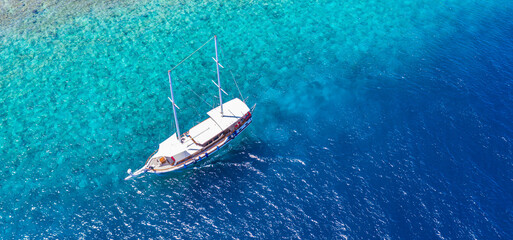 Sailing yacht in Maldives islands. Aerial drone view of white sailboat anchored, crystal clear...