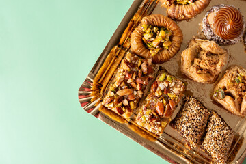 Assortment of Ramadan dessert baklava and dates on green background