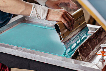 selective focus photo of male hands with squeegee. serigraphy production. printing images on...