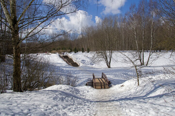 A bridge over a stream at the bottom of a small ravine.