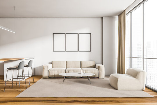 Beige sofa in living room interior with kitchen and three posters
