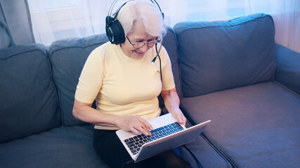 Elderly woman with headset having video call with family and waving to camera. Old people and...