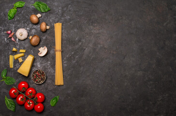 Ingredients for cooking on black dackground with copy space. Spaghetti tomatoes mushrooms cheese basil garlic and pepper on black background.