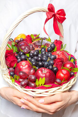 Wicker basket in hands with fruit and a bottle of wine, For a holiday or a picnic.