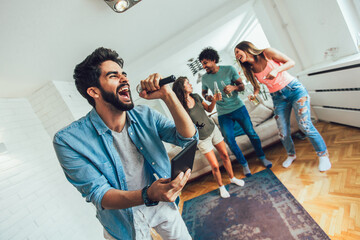 Group of friends playing karaoke at home. Concept about friendship, home entertainment and people