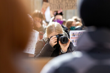 A photographer holds a camera and takes pictures.