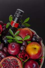 Wicker basket with fruit and a bottle of wine, beautifully decorated on a dark background. concept., congratulations for a holiday or picnic.