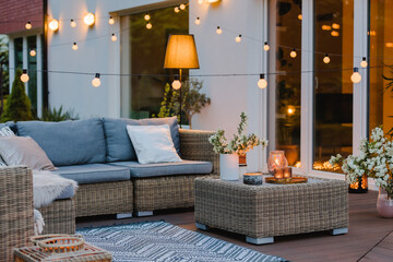 Summer evening on the terrace of beautiful suburban house with patio with wicker furniture and...